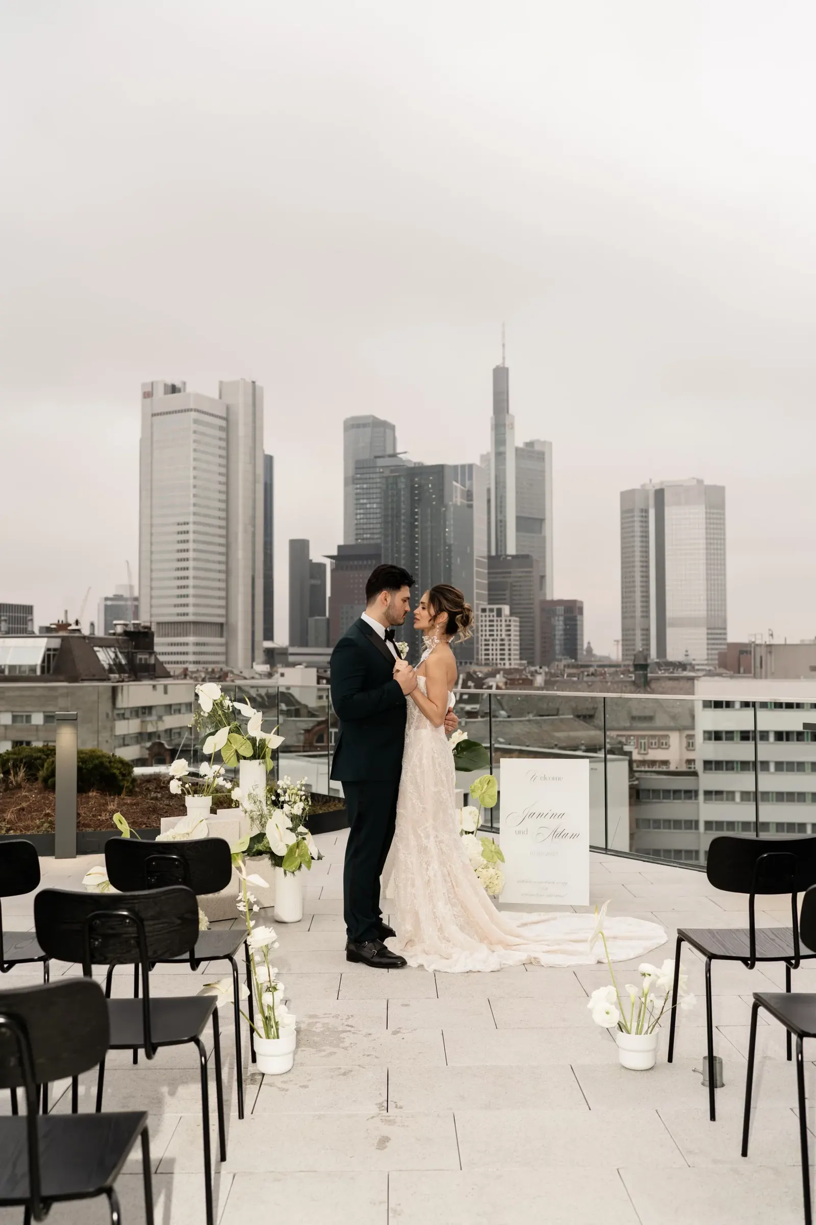 A bride and groom on a rooftop terrace with the Frankfurt skyline in the background