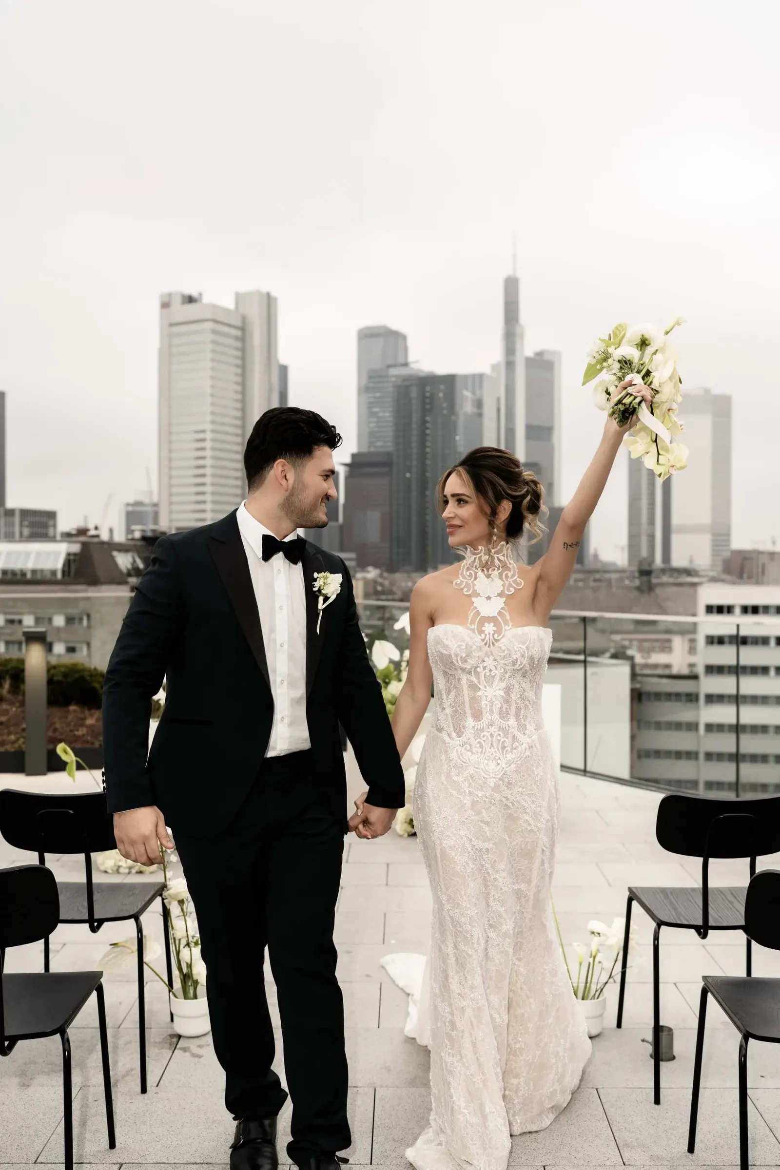 A bride and groom holding a bouquet in front of the Frankfurt skyline